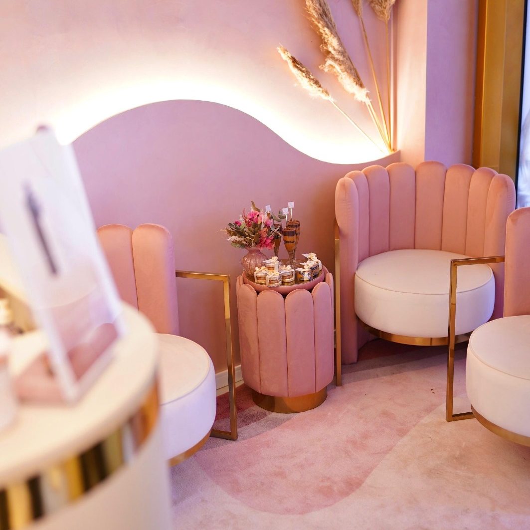 Lounge de espera do salão em tons de rosé e dourado